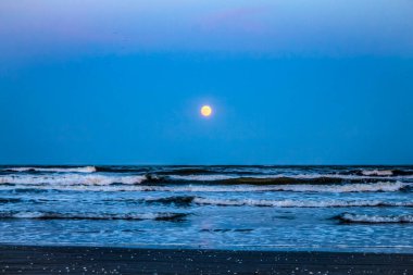 Deniz dalgaları ve ay ile güzel bir gece manzarası