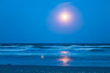 Denizin üzerinden gece görüşü Ay ve ufukta yıldızlarla