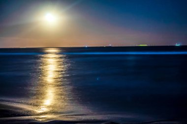 Ay ve deniz feneri olan güzel bir deniz manzarası