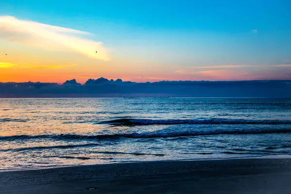 Sahilde gün batımı Renkli bir gökyüzü ve bulutlarla