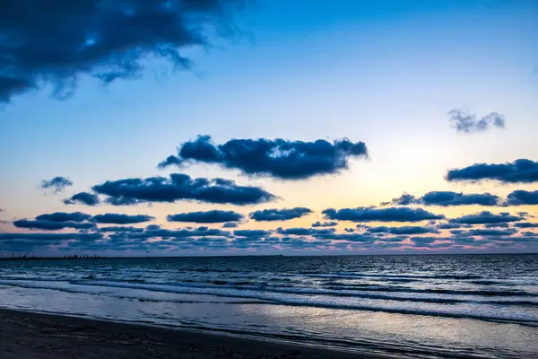 Baltık Denizi 'nde güzel bir gün doğumu. Kumsal çok kumlu, deniz görülebilir ve büyük bir dalga var..