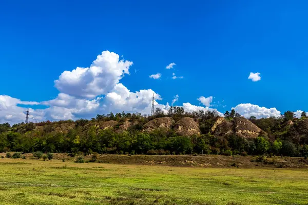 Mavi gökyüzü ve beyaz bulutlarla dolu bir arazi.