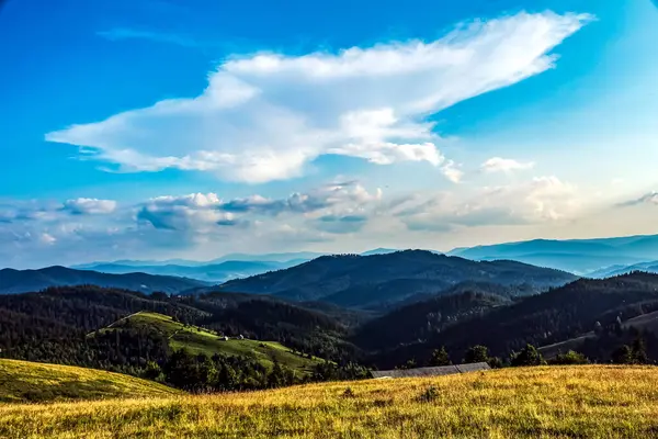 Bulutlu ve mavi gökyüzü olan dağ manzarası