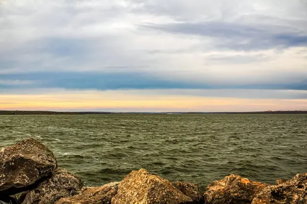 Gün batımının arka planında kayalar olan güzel bir deniz manzarasının dikey çekimi.