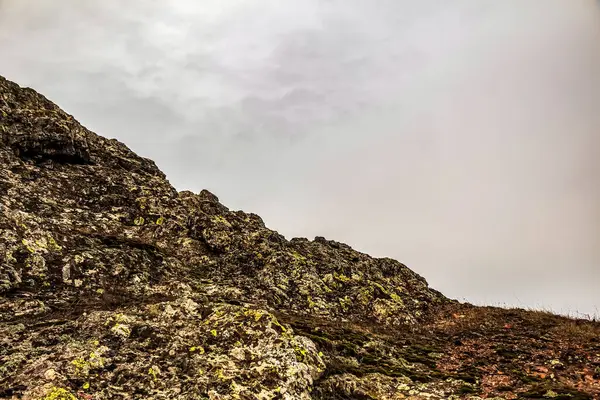 Arka planda bulutlu bir gökyüzü olan kayalık bir dağın yakın çekimi