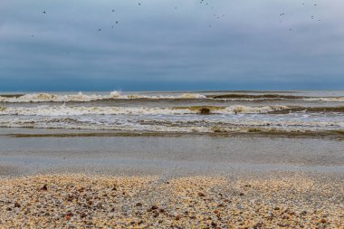 Deniz kıyısında dalgalar ve bulutlu gökyüzü