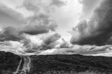 Tepelerin üzerinde siyah beyaz fırtına bulutları