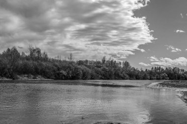 Nehrin üzerinde siyah beyaz bulutlar ve arka planda su.