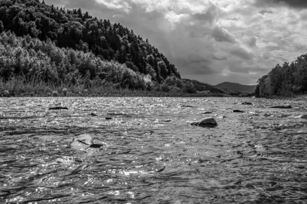 Güzel bir dağ nehrinin siyah beyaz fotoğrafı.