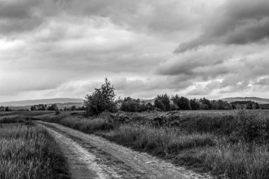 Kırsal bir yol üzerinde siyah ve beyaz bulutlar