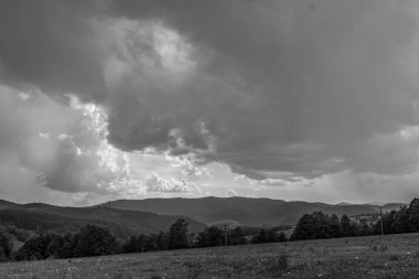Dağların üzerindeki fırtına bulutlarının gri tonlu görüntüsü.