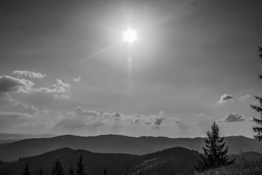 Yazın dağlarda güneş bulutların arasından parlar..