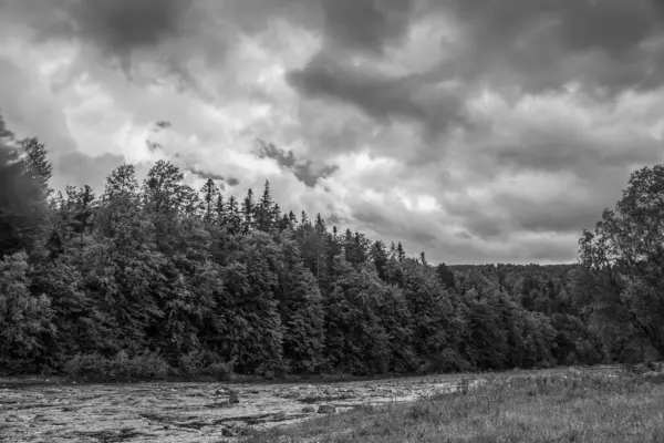 Nehir üzerinde kara fırtına bulutları, yağmurda yeşil orman