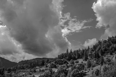 bulutlu bir gün ile bir dağ manzarasının siyah beyaz fotoğrafı
