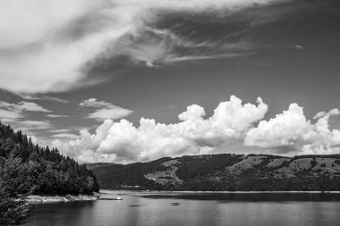 Göl ve dağların üzerinde siyah ve beyaz bulutlar