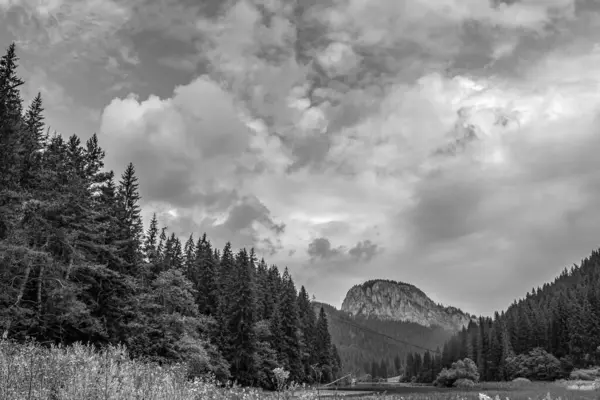 Siyah beyaz bulutlar ve arka planda dağlar