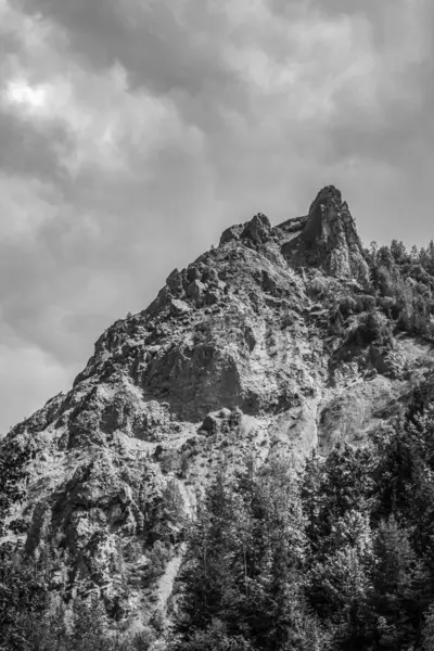 Bulutlu bir gökyüzünün altındaki kayalık dağların güzel bir görüntüsü.