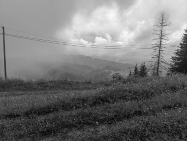 Dağların üzerinde siyah beyaz bulutlar