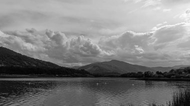 Siyah ve beyaz bulutların arkasındaki dağ nehri.