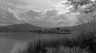 Gölün arka planında siyah beyaz bulutlar