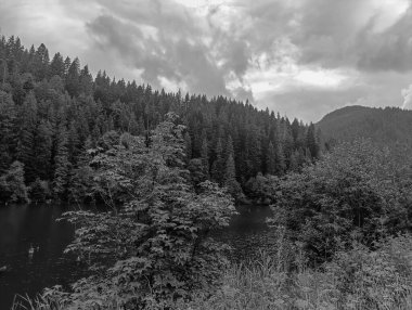 Dağlarda bulutlu bir nehri olan güzel siyah ve beyaz dağ manzarası.