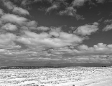 Kara ve beyaz bulutlar karlı bir kış manzarasının üzerinde