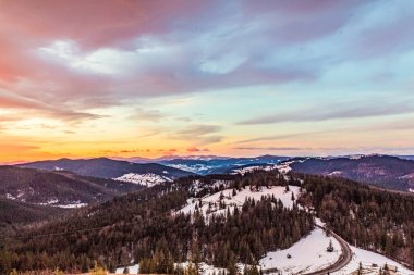 Kışın dağlarında gün batımı. Güneş 'in ışınları. Dağlar karla kaplı,