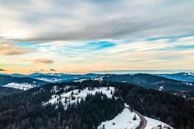 Gün batımında ormanla kaplı kış dağının havadan görünüşü