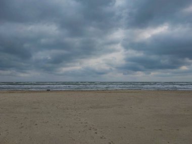 Arka planda büyük bir fırtına olan bir deniz kıyısı manzarası