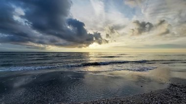 Bulutların arkaplanındaki güzel deniz manzarası. Denizde gün batımı. Dalgalar suya yansıyor..