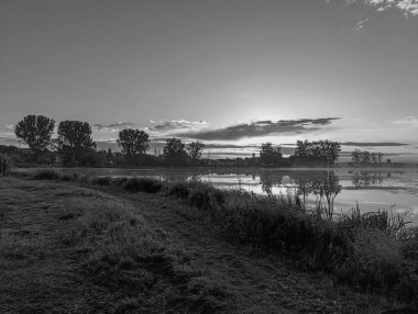Etrafı yeşillik ve ağaçlarla çevrili güzel bir nehir görüntüsü.
