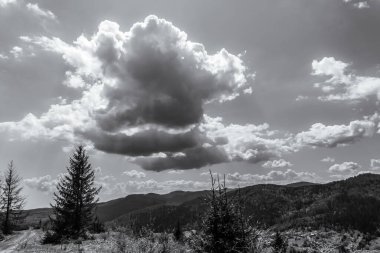 Önünde beyaz bir bulut olan bir dağın güzel gri tonlu görüntüsü.