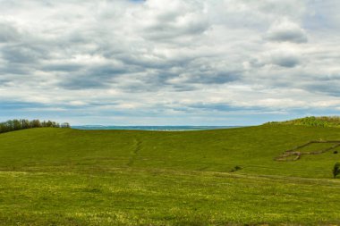 Yeşil çayır ve mavi gökyüzü olan güzel bir arazi manzarası.