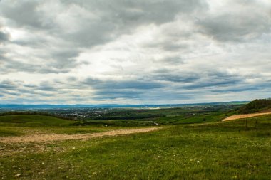 Bulutlu bir gökyüzünün altında bulutlu bir arkaplan ile güzel bir yeşil tarla manzarası