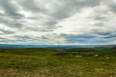 Yeşil arazili ve bulutlu bir gökyüzü.