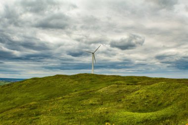 Rüzgâr türbini yeşil alanda Dağlarda bulutlar