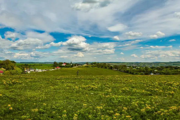Tarlanın ortasındaki güzel manzaralı küçük bir köy. Önünde mavi bir gökyüzü var..