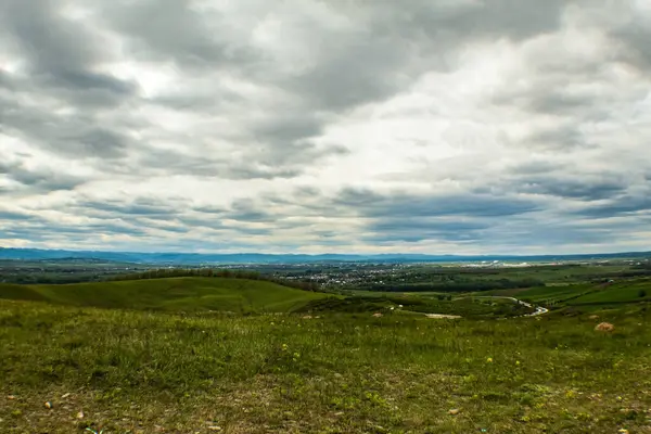 Yeşil arazili ve bulutlu bir gökyüzü.
