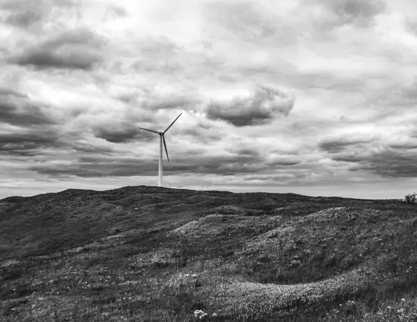 Tepedeki yel değirmeninin gri tonlu görüntüsü.