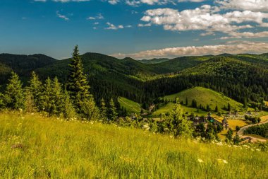 Dağları olan güzel bir manzara ve arkasında mavi bir gökyüzü.