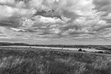 Yazın tepeler ve tarlalar üzerinde siyah ve beyaz bulutlar