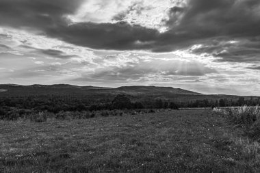 Bulutlu gökyüzü ile tepelerin manzarasının güzel bir görüntüsü.