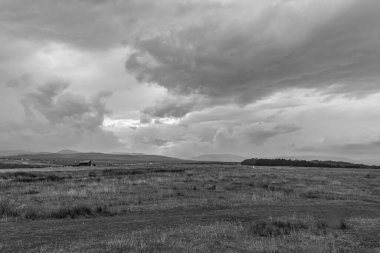 Dağların üzerinde siyah beyaz bulutlar