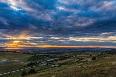a beautiful view of a field of grass under a cloudy sky at sunset