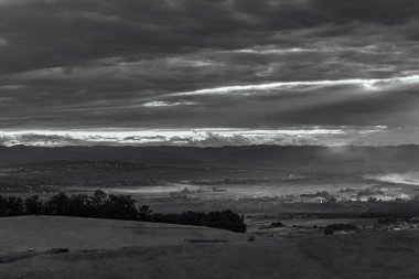 a beautiful shot of a landscape with clouds and hills in a background