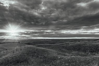 Bulutlarla dolu bir tarlası ve bulutlu gökyüzü olan güzel bir manzara.