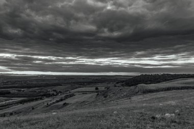 the landscape of the black and white clouds in the background