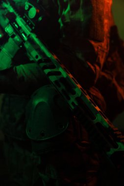 Üniformalı asker. Yüksek kaliteli 4K görüntüler. Tam teçhizatlı kararlı bir asker dumanlı, atmosferik bir sahnede yürüyor. Yoğun ve renkli ışıklandırmayla aydınlatılıyor.. 