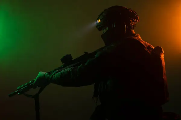 Üniformalı asker. Yüksek kaliteli 4K görüntüler. Tam teçhizatlı kararlı bir asker dumanlı, atmosferik bir sahnede yürüyor. Yoğun ve renkli ışıklandırmayla aydınlatılıyor.. 