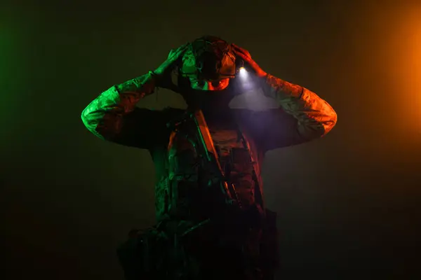 Üniformalı asker. Yüksek kaliteli 4K görüntüler. Tam teçhizatlı kararlı bir asker dumanlı, atmosferik bir sahnede yürüyor. Yoğun ve renkli ışıklandırmayla aydınlatılıyor.. 